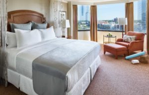 Guestroom with grey linens and view of the city