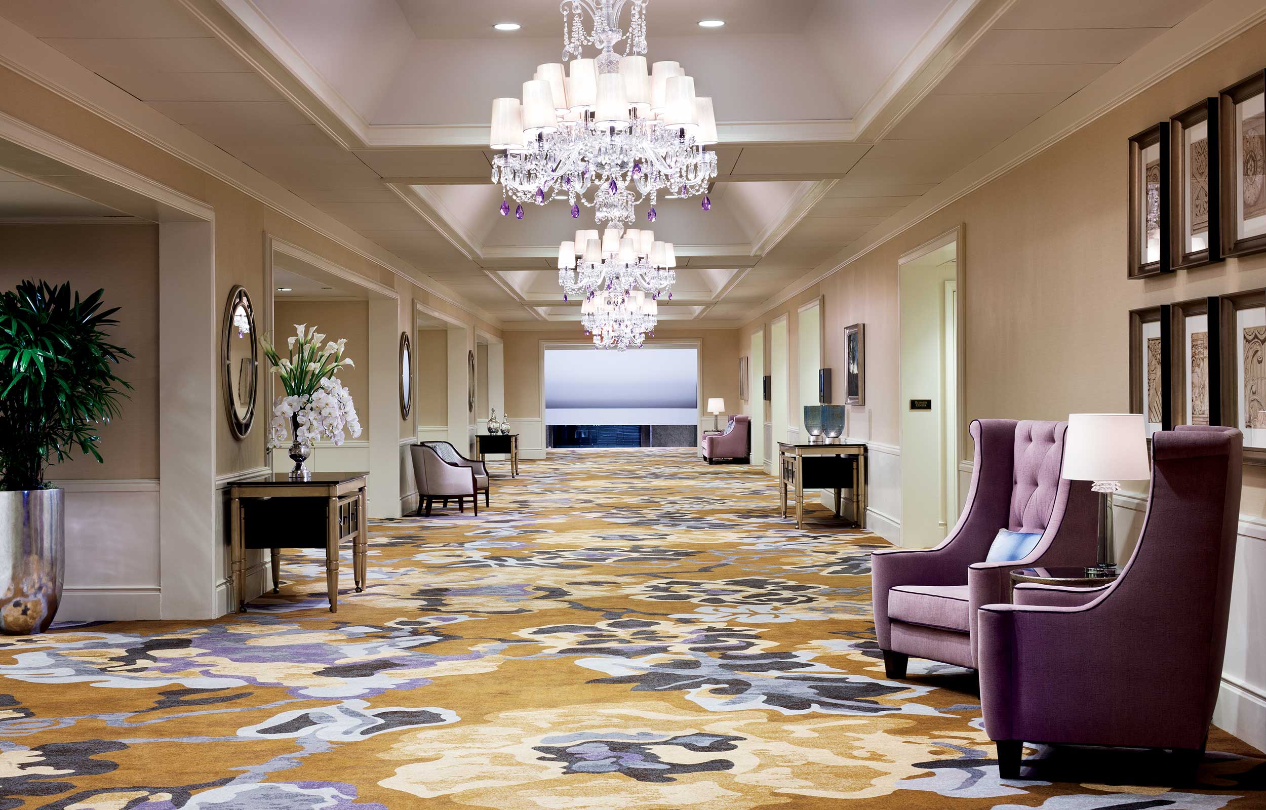 Large hallway with chandeliers and purple seating